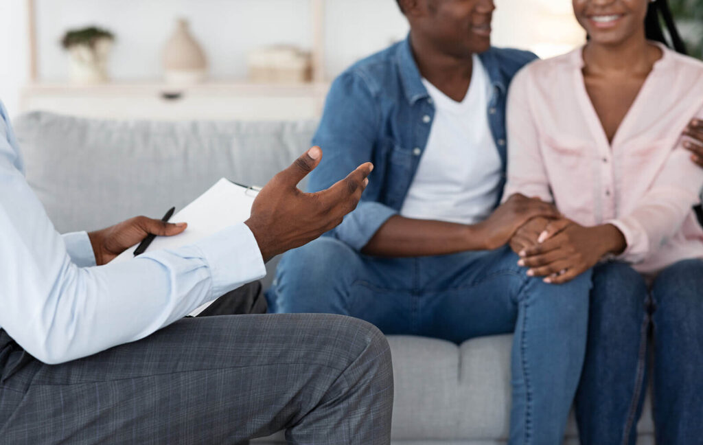 Couple smiling during therapy | multicultural couple therapy in south bay, ca | eft couples therapy in hermosa beach, ca | interracial couples therapist | Hermosa Beach CA | 90266 | 90277 | South Bay CA 90226 | 90248 A happy couple smiling and sitting on a couch during a couples therapy session. Contact an intercultural couples therapist in South Bay, CA, to learn more about multicultural marriage counseling. EFT couples therapy can help you reconnect with your partner.