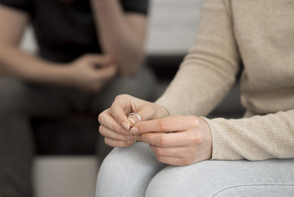A woman holding her wedding band in her hand. Before contemplating separation or divorce, contact a multicultural couples therapist in Hermosa Beach, CA today. Learn about the benefits of EFT therapy for couples and the challenges interracial couples often face.