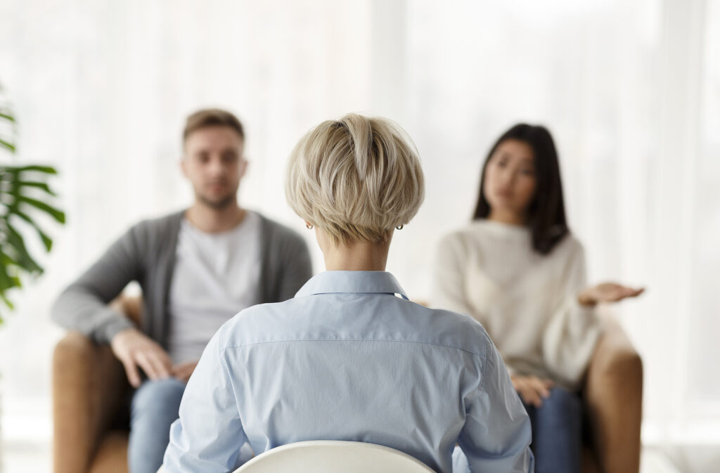 A woman sits with her back to the camera in a chair across from a couple. This could represent overcoming relationship issues with a relationship therapist in Hermosa Beach, CA. Learn more about interracial relationships in South Bay, CA and how individual therapy for relationship issues can support you in Torrance, Palos Verdes, and more!
